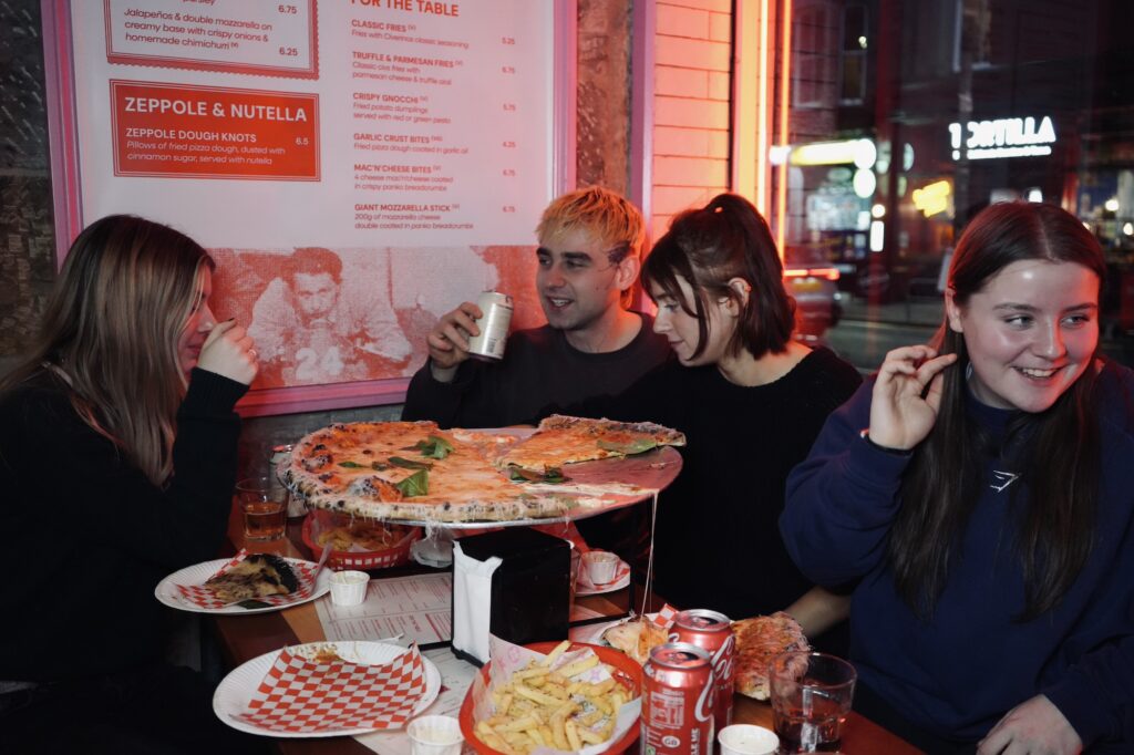 Group of students at Civerinos table with lots of pizza slices
