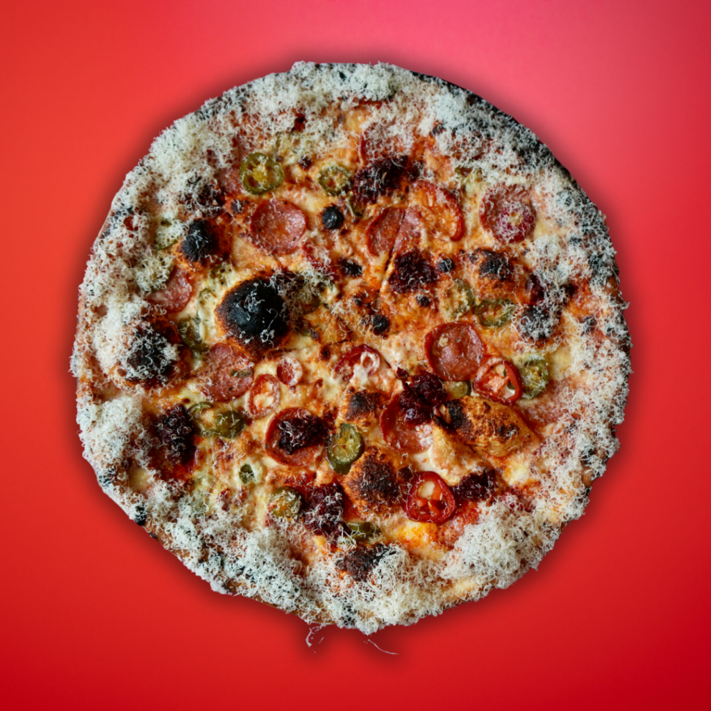 Pickled jalapeno and pepperoni New York pizza on red background