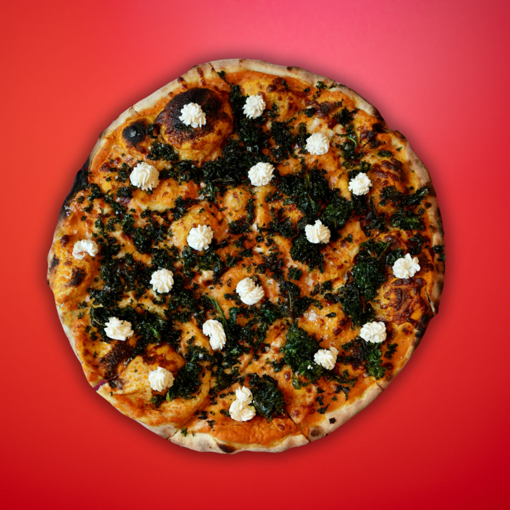 Crispy kale, truffle whipped ricotta & Hebridean rocksalt on sweet potato puree & mozzarella base - New Haven pizza on red background