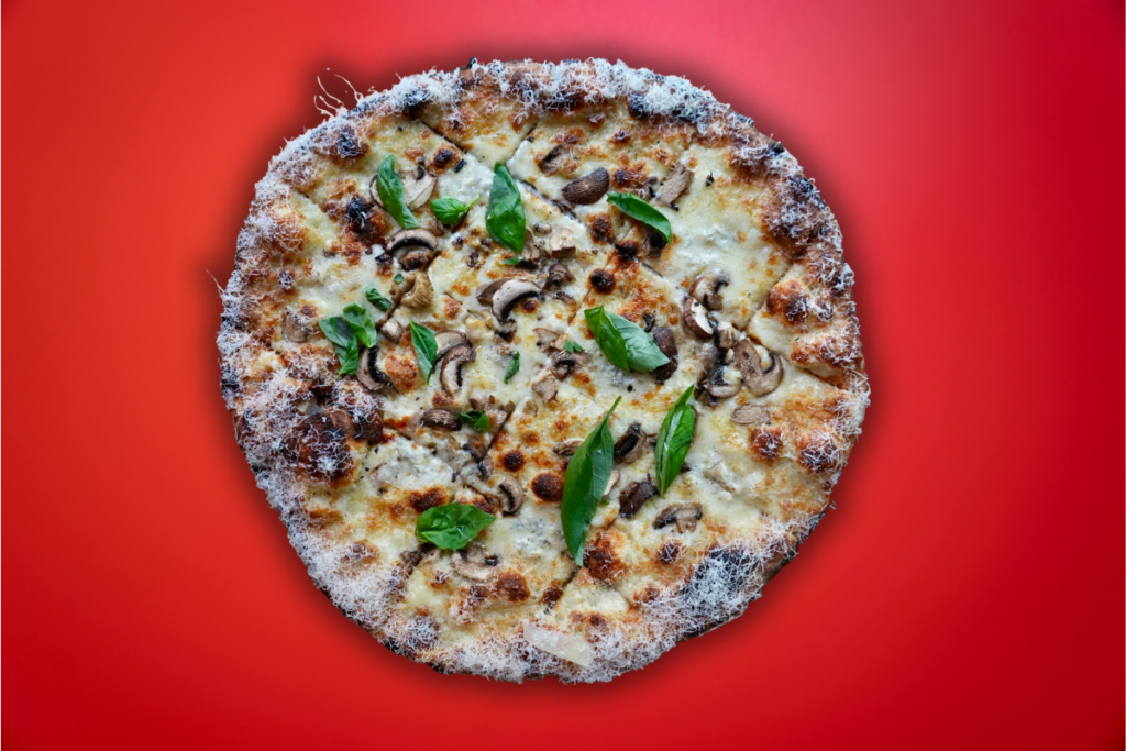 3 cheese and wild mushroom new haven style pizza with red background