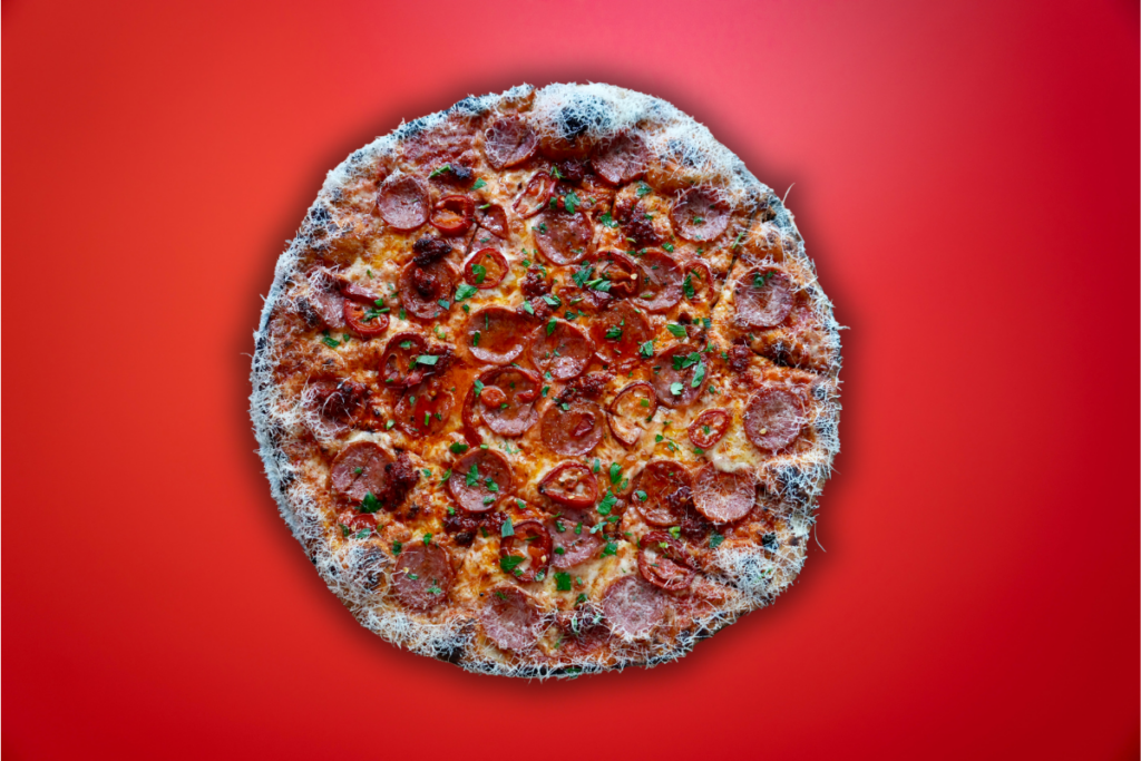 whisky nduja, pickled jalapenos and pepperoni on New Haven style pizza with red background